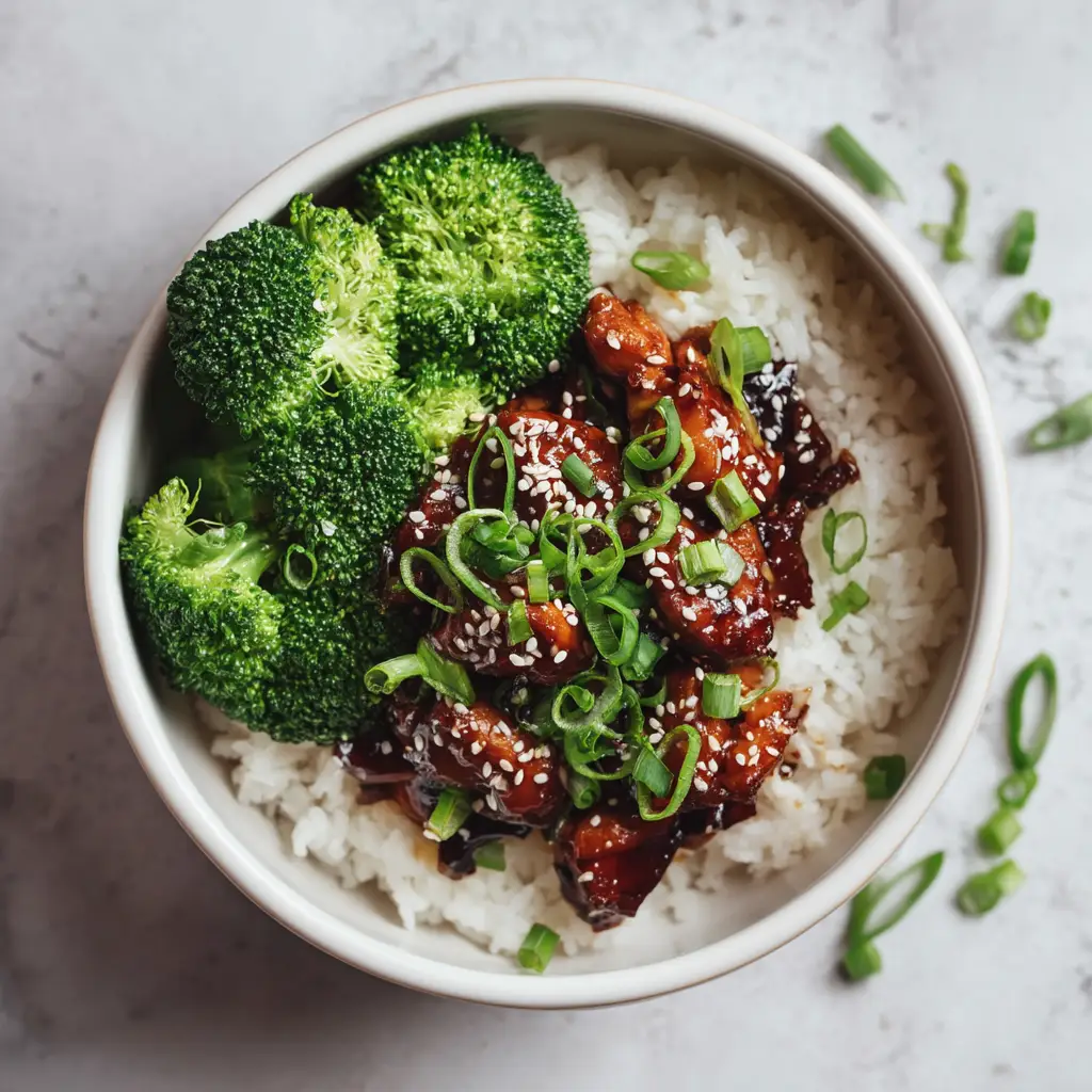 A close-up shot of the glossy, homemade teriyaki sauce glazing the juicy pieces of chicken in the bowl.