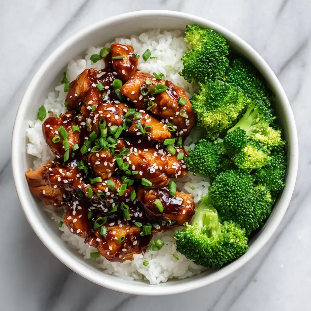 An overhead shot of a homemade teriyaki chicken bowl with fresh broccoli, carrots, and a sprinkle of sesame seeds.
