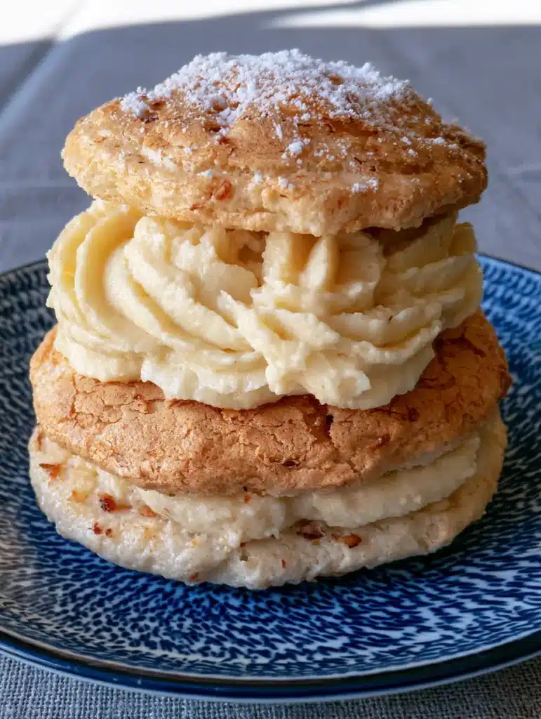 Close-up of golden-brown French Almond Cookies with visible ground almonds and thick ivory cream filling.