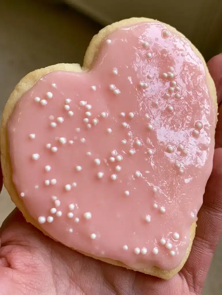 Sugar Cookie Icing That Hardens: The Secret to a High-Gloss Professional Finish 1 Macro shot of white sugar pearl sprinkles on glossy pink icing. (Sugar Cookie Icing That Hardens)